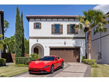 Elegant two-story home with a red tile roof, beautiful landscaping, brick driveway, and a red Ferrari in front at 8113 Via Vittoria Way, Orlando, FL 32819