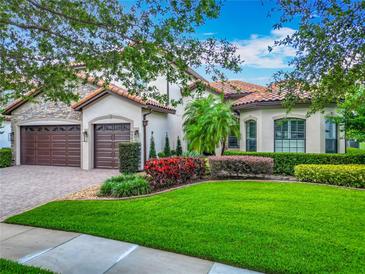Charming home featuring a three-car garage, lush landscaping, and a tile roof at 9942 Hatton Cir, Orlando, FL 32832