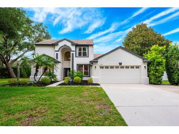 Beautiful two-story home with a manicured lawn, arched entry, and two-car garage, all under a bright blue sky at 10241 Pointview Ct, Orlando, FL 32836