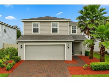 Charming two-story home with a brick driveway, two-car garage, and lush landscaping including palm trees at 17416 Painted Leaf Way, Clermont, FL 34714