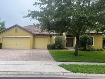 Charming single-story home with a brick driveway, a well-manicured lawn, and mature trees providing ample shade at 3904 Coastal Breeze Dr, Kissimmee, FL 34744