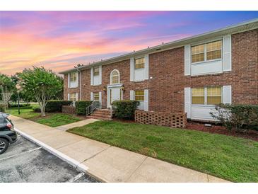 Charming brick townhouse with white shutters, a manicured lawn, and lovely landscaping at 4300 Lake Underhill Rd # D, Orlando, FL 32803