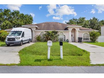 Charming single-story home with arched windows, a green lawn and mature landscaping at 621 Bluebill Ln, Poinciana, FL 34759
