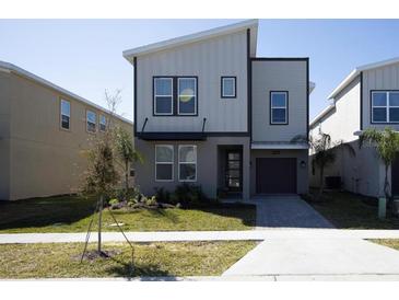 Modern two-story home featuring a minimalist design, neutral color palette, and well-manicured lawn at 8986 Cabot Cliffs Dr, Davenport, FL 33896