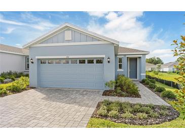 Charming one-story home with light-blue exterior, well-manicured landscaping, and brick-paved walkway and driveway at 9108 Wildlight, Wildwood, FL 34785