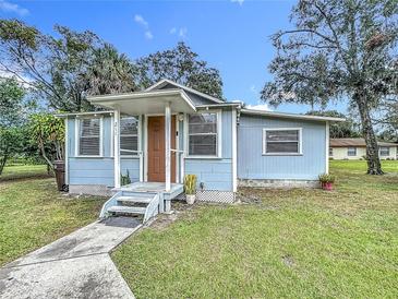 Charming single-story home featuring a covered front porch, mature trees, and well-maintained landscaping at 211 N Randolph Ave, Kissimmee, FL 34741