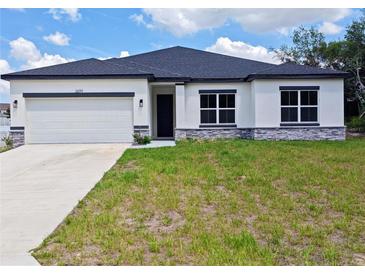 Charming single-story home with a white exterior, dark roof, and an attached two-car garage at 2699 Sw 161St Loop, Ocala, FL 34473