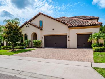 Beautiful home featuring a red tile roof, a three-car garage and a lovely brick driveway and tropical landscaping at 8047 Chilton Dr, Orlando, FL 32836