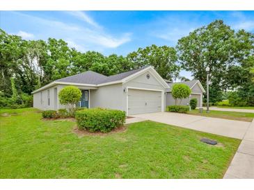 Charming single-story home with well-manicured lawn and two-car garage nestled among mature trees at 907 Pearly Ridge Ln, Lakeland, FL 33809