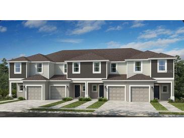 Modern townhome exterior featuring multiple units, individual garages, and manicured landscaping at 134 River Front Way, Edgewater, FL 32141