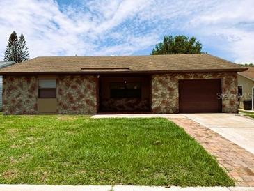 Charming single-story home featuring a stone facade, lush lawn, and attached garage at 2842 Blind Owl Dr, Orlando, FL 32822