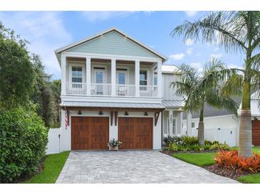 Beautiful two-story home featuring a spacious front porch and a well-manicured lawn with lush landscaping and a paved driveway at 507 S Pine St, New Smyrna Beach, FL 32169
