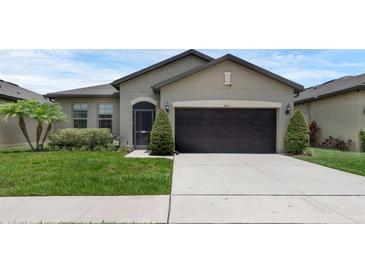 Charming one-story home featuring a two-car garage, manicured lawn, and decorative landscaping at 8615 N Rindge Rd, Polk City, FL 33868