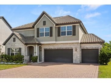 Charming two-story home with a three-car garage, tile roof, stone accents, and well-manicured landscaping at 2340 Standing Rock Cir, Oakland, FL 34787
