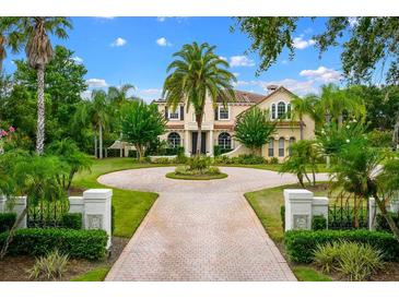 Beautiful estate featuring a circular driveway, lush landscaping, and a grand facade with classic architectural details at 2357 Alaqua Dr, Longwood, FL 32779
