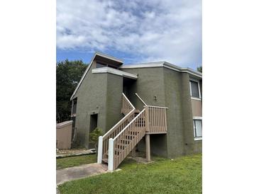 View of the building featuring an entrance staircase on the upper level and green painted exterior at 5784 Peregrine Ave # A08, Orlando, FL 32819
