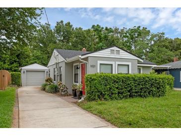 Charming single-story home featuring a well-manicured lawn, a detached garage, and a welcoming red front door at 1021 N Forest Ave, Orlando, FL 32803