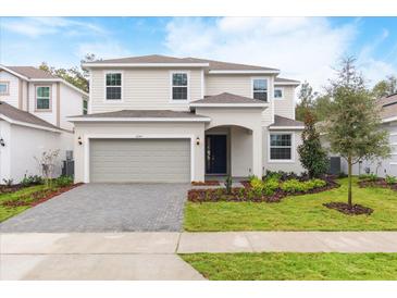 Two-story home featuring a two-car garage, brick driveway, and manicured lawn at 2261 Sirena Ln, Mount Dora, FL 32757