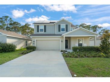 Charming two-story home featuring a two-car garage, manicured lawn, and energy-efficient solar panels at 3941 Willowbrook Dr, Edgewater, FL 32141