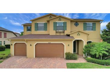 Charming two-story home featuring a three-car garage, beautiful green shutters, and a brick driveway at 4265 Foxhound Dr, Clermont, FL 34711
