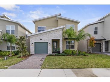 Charming two-story home with a stone accent wall, a green garage door, and a well-manicured lawn at 9227 Sommerset Hills Dr, Davenport, FL 33896