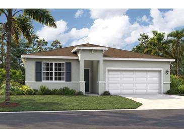 Charming single-story home featuring a two-car garage, front yard, and tropical landscaping at 928 Pearlwood Loop, Eagle Lake, FL 33839