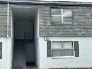 Building exterior featuring gray shingles, white paint, and an entryway with staircase to upper units at 1000 S Semoran Blvd # 608, Winter Park, FL 32792