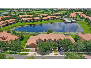 Stunning aerial view of community featuring a serene lake, pool, lush greenery, and well-maintained townhome exteriors at 10308 Belfry Cir, Orlando, FL 32832