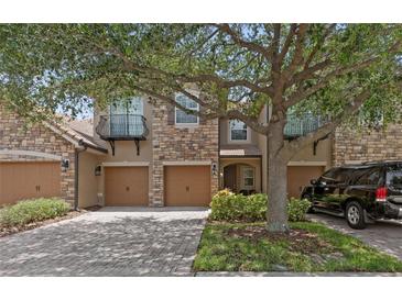 Attractive townhome exterior featuring stone accents, a private balcony, multi-car garage, and lovely tree at 10308 Belfry Cir, Orlando, FL 32832