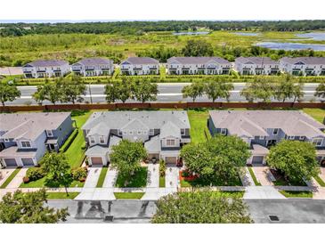Beautiful aerial view of townhomes with manicured lawns, mature trees, and a scenic view of a lake at 1784 Fritwell Ct, Ocoee, FL 34761