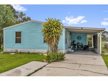 Charming home featuring light blue siding, carport, and lush green lawn at 222 Ellsworth Dr, Kissimmee, FL 34758
