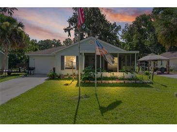 Charming single-story home with a well-manicured lawn, screened in porch, and American flags displayed at 2597 Cr 426F, Lake Panasoffkee, FL 33538