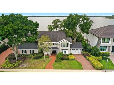 Stately two-story home featuring mature trees, a brick driveway, and an attached two-car garage at 9146 Bay Point Dr, Orlando, FL 32819