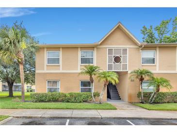 Charming condo exterior with tan walls, palm trees and manicured landscaping, and a blue sky at 9900 Sweepstakes Ln # 1, Orlando, FL 32837