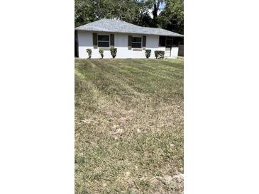 Charming single story home with tidy landscaping, brown shutters and a grey roof at 1030 Nw 13Th Ave, Ocala, FL 34475
