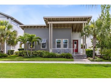 Charming two-story home with gray siding, covered porch, landscaped yard, and a red front door at 13334 Beebe Aly, Orlando, FL 32827