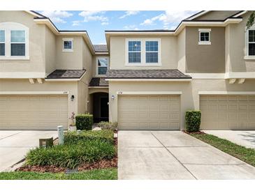 A view of the townhome's exterior, showcasing a well-maintained front yard and attached garages at 178 Windflower Way, Oviedo, FL 32765