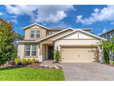 Charming two-story home with landscaped yard, tan siding, and a brick driveway under a sunny sky at 2335 Green Symphony Pl, Oviedo, FL 32765