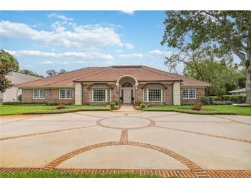 Stunning front exterior with circular driveway, lush landscaping, and inviting entrance with a tile roof and stone facade at 3215 Greens Ave, Orlando, FL 32804