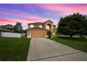 Inviting two-story home featuring an arched entryway, attached two-car garage, and a lush front lawn at dusk at 442 Churchill Ct, Kissimmee, FL 34759