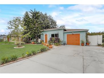 Charming single-story home with light blue exterior, orange doors, and beautiful landscaping at 840 Del Prado Dr, Kissimmee, FL 34758
