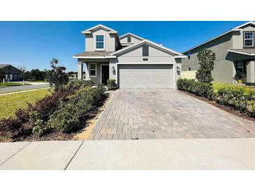 Charming two-story home with neutral color, a brick driveway, and beautiful landscaping at 2807 Alder Berry Blvd, Ocoee, FL 34761