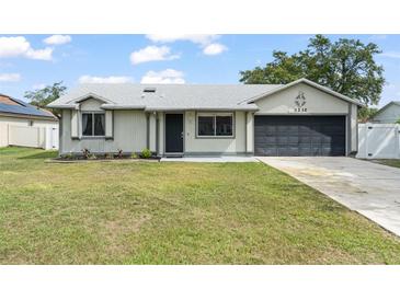 Charming one story home with a well-maintained lawn, gray exterior, and a two-car garage at 3232 Butterfield St, Deltona, FL 32738