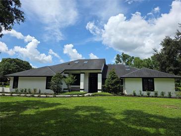 Stunning single-story home with a well-manicured lawn and modern architectural design, under a partly cloudy blue sky at 4454 Aspenwood Ct, Orlando, FL 32835