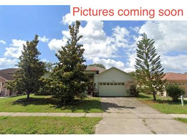 Charming one-story home with a two-car garage, mature trees, and well-maintained lawn at 451 Acacia Tree Way, Kissimmee, FL 34758