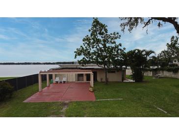 View of the backyard with patio, chairs, lush lawn, and lakefront access, perfect for outdoor living at 5529 Hansel Ave, Orlando, FL 32809