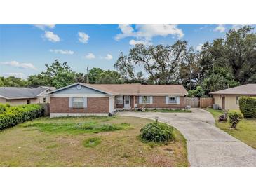 Charming single-story home featuring a brick facade, light blue trim, and a spacious front yard with a circular driveway at 5812 Viking Rd, Orlando, FL 32808