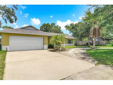 Charming single-story home featuring an attached two-car garage and a lush front yard with mature trees at 700 E Mattie St, Sanford, FL 32773