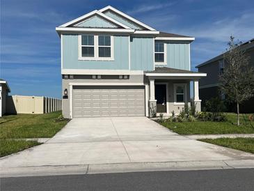 Charming two-story home featuring light blue siding, a spacious driveway, and a two-car garage at 930 Cattleman St, Winter Haven, FL 33881