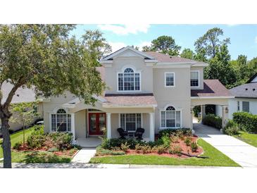 Charming two-story home featuring a landscaped yard, red front door and an attached covered garage at 14044 Chicora Crossing Blvd, Orlando, FL 32828